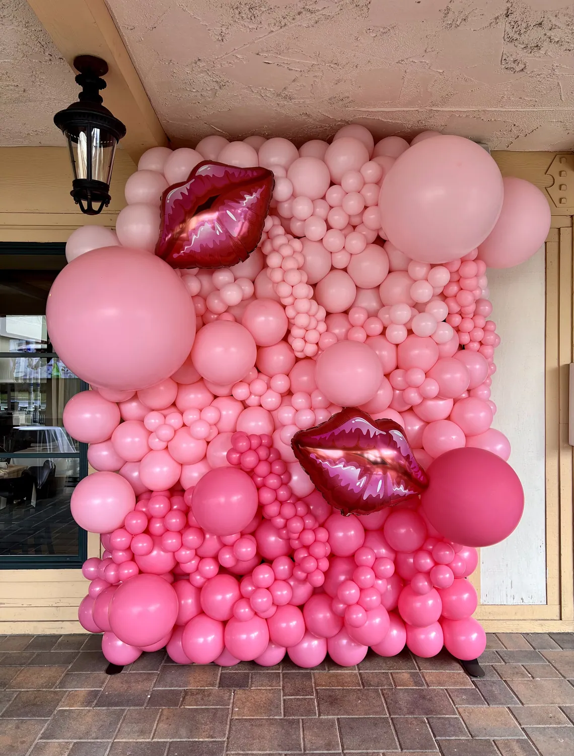 Dense pink balloon mosaic wall with two foil lips.