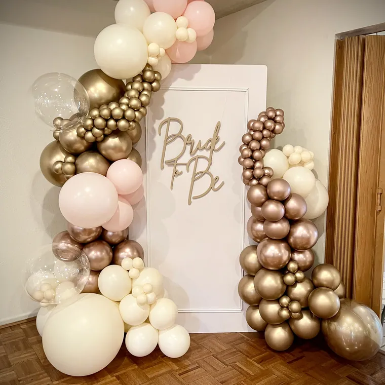 Blush, cream and gold balloon garland beside a Bride to Be sign.