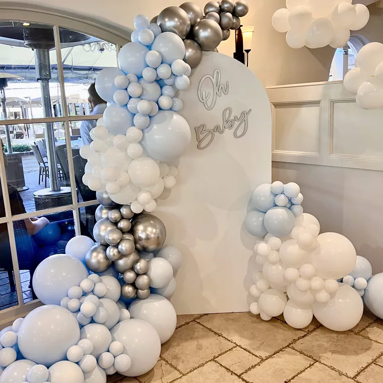 Pale blue and white balloon backdrop with an Oh Baby sign.