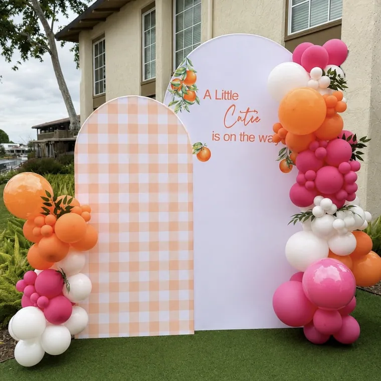 Pink and orange balloon backdrop against gingham and plain arched panels.