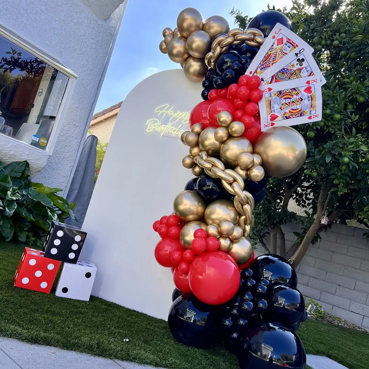 Red, navy and gold balloon backdrop with playing card props.