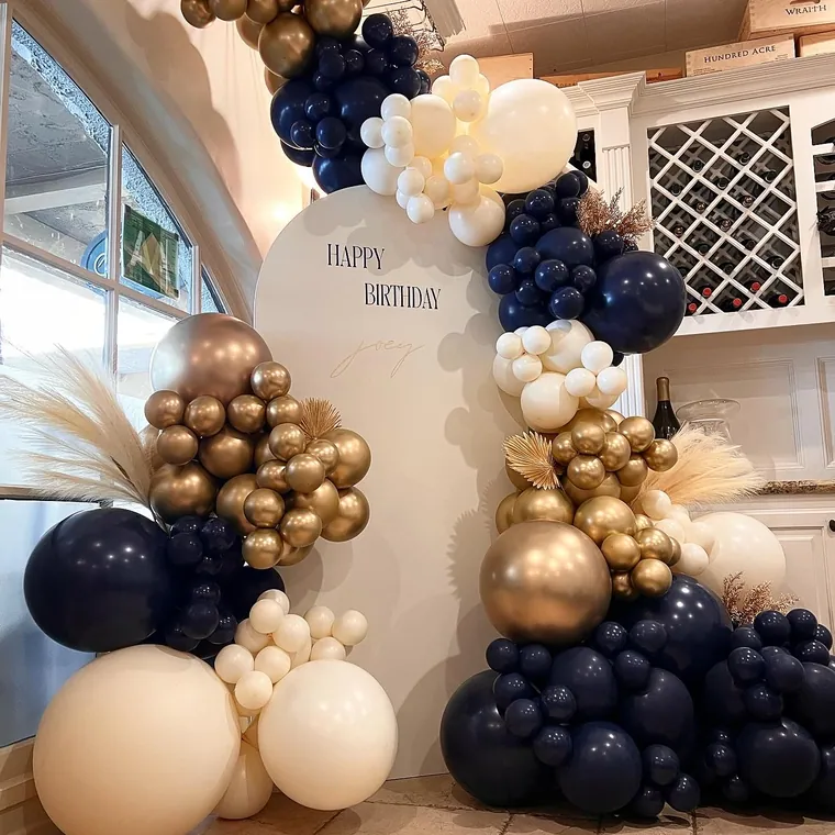 Navy, gold and cream balloon backdrop with pampas against an arched panel.