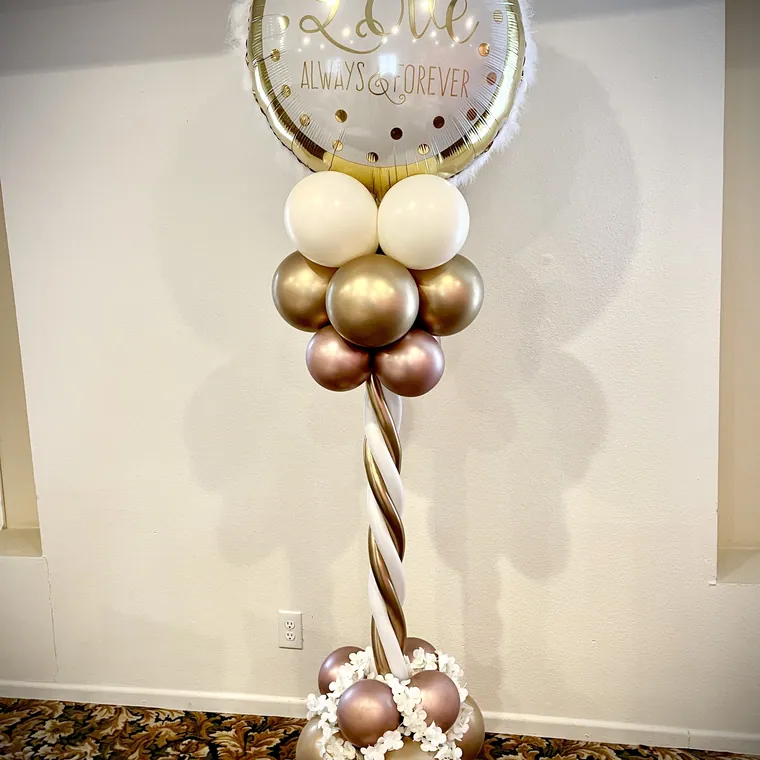 Close view of a gold chrome and matte cream balloon bouquet with a printed topper.