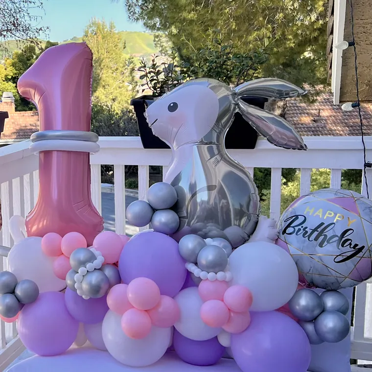 Pink, lilac and silver balloon cluster around a foil number one.