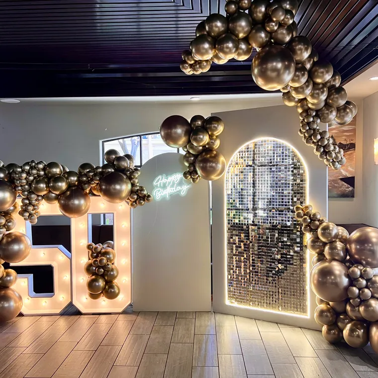 Chrome gold balloon garland running across a dark restaurant ceiling.