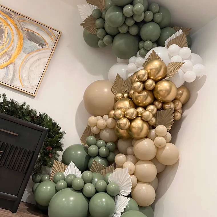 Close view of a sage, cream and gold balloon garland with dried palm fans.