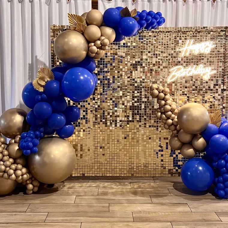 Detail of a gold sequin wall framed by navy, gold and cream balloons.