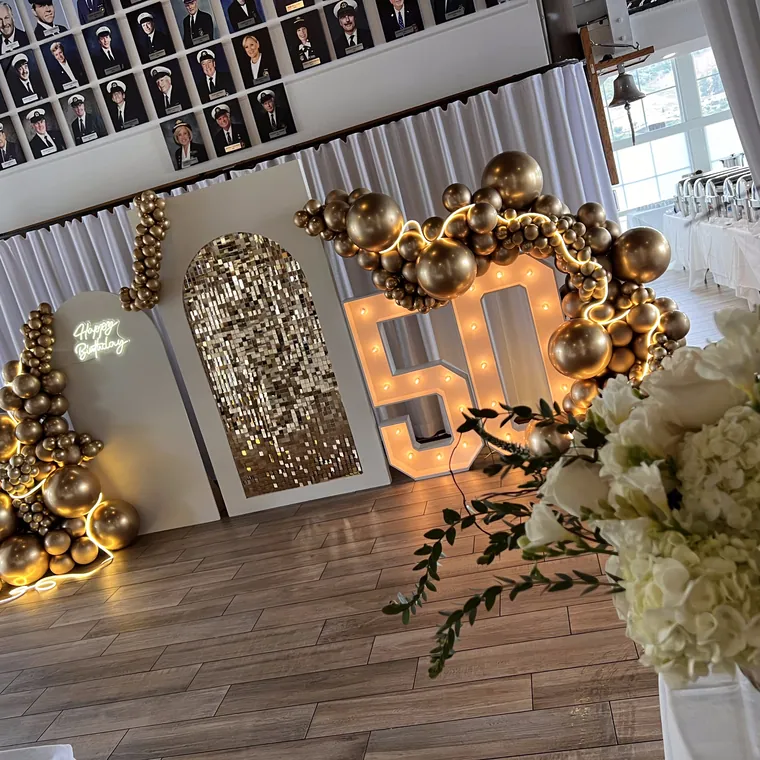 Light-up 50 with a gold balloon garland in a venue dining room.
