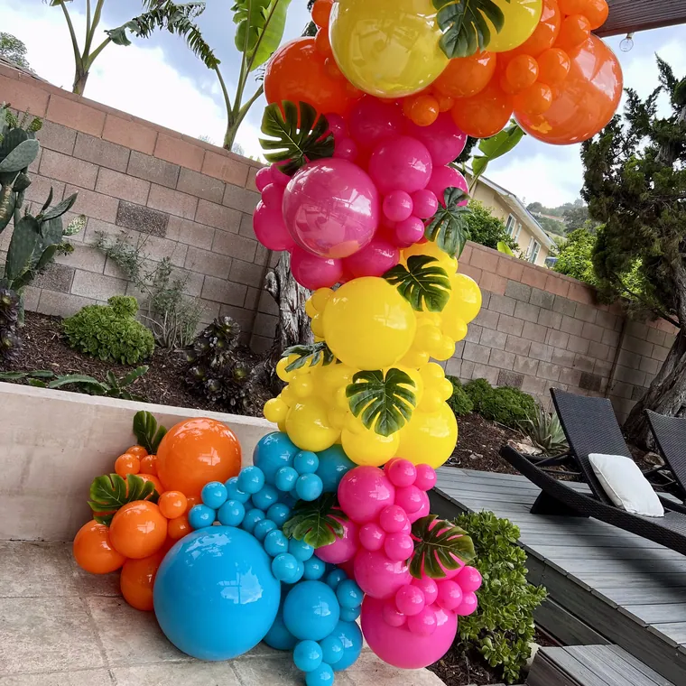 Tropical balloon column in pink, yellow and blue with palm leaf foils.