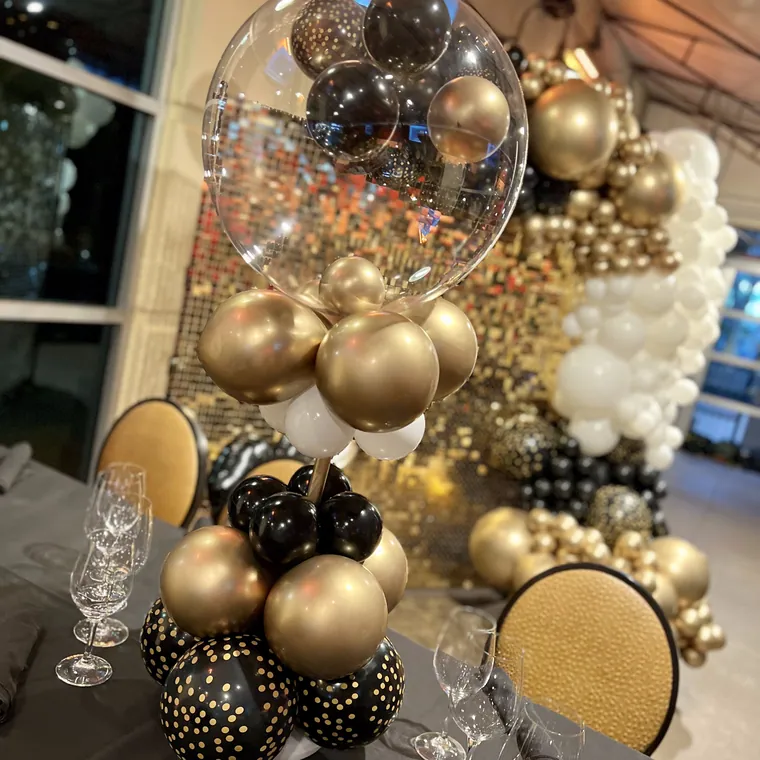 Black and gold balloon styling on a table with clear bubble balloons.