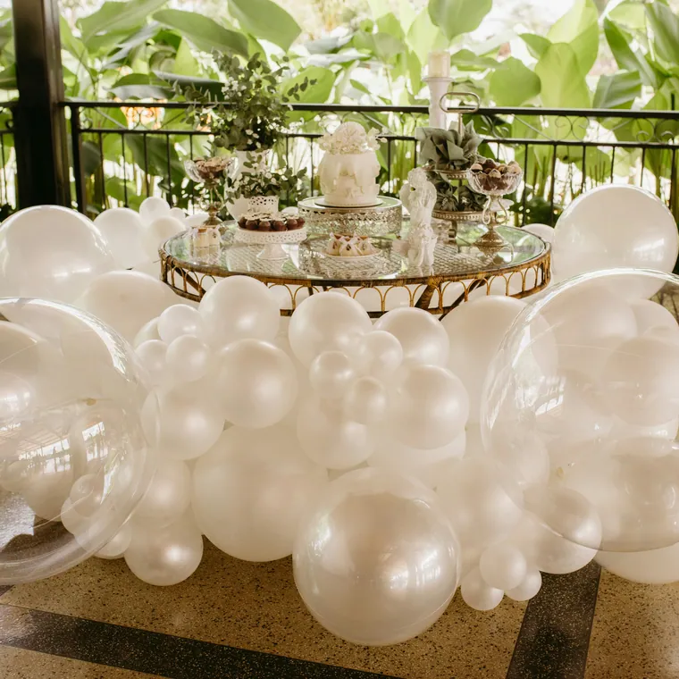 Clear and white balloon garland running along the base of a cake table.