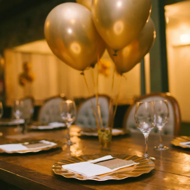 Gold chrome balloon bouquet on a long set dining table.