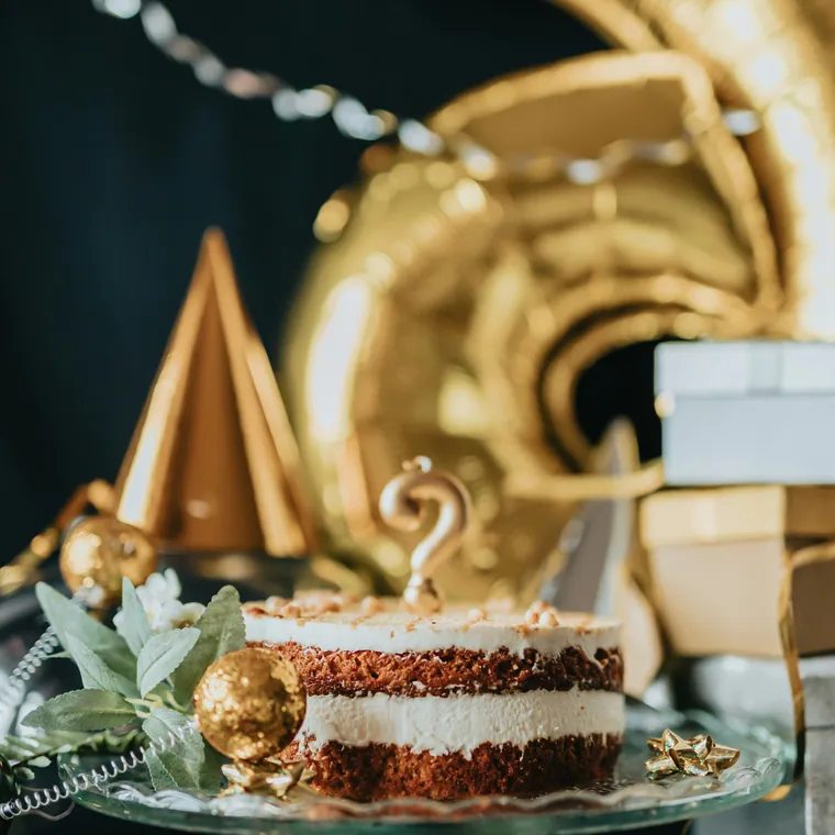 Gold foil numbers and confetti styling behind a naked cake.