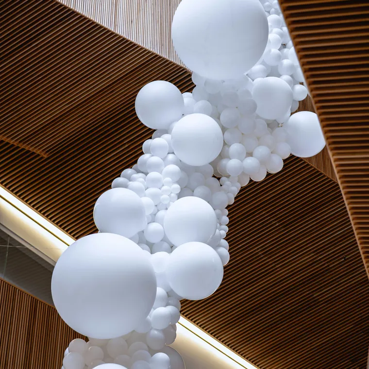 White balloon garland running along a curved timber ceiling.