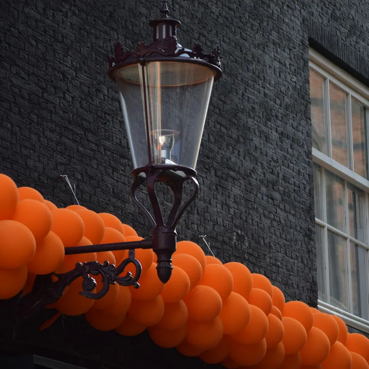 Orange balloon garland running along a black brick shopfront.
