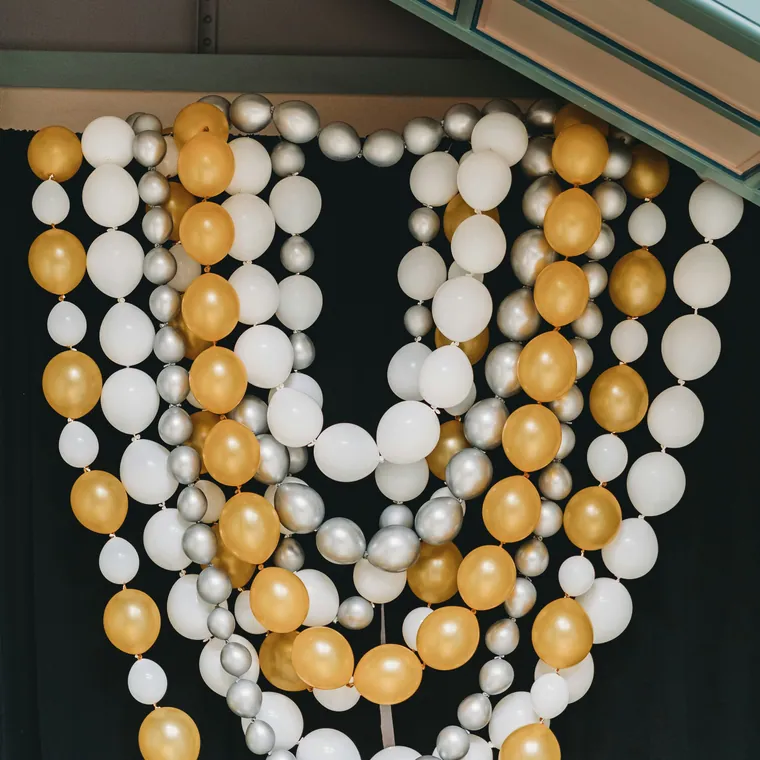 Gold and white balloon swags hung in loops across a dark wall.