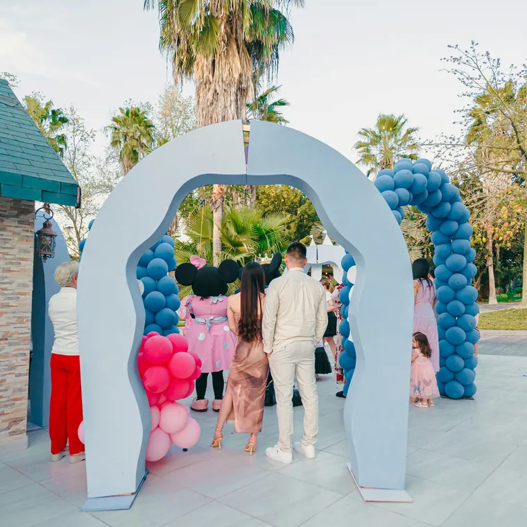 A run of blue and white balloon arches forming a walkway outdoors.