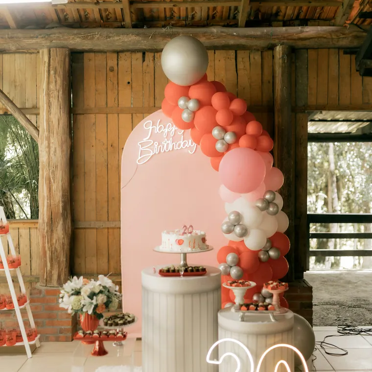 Blush and white balloon arch around an arched panel inside a barn.