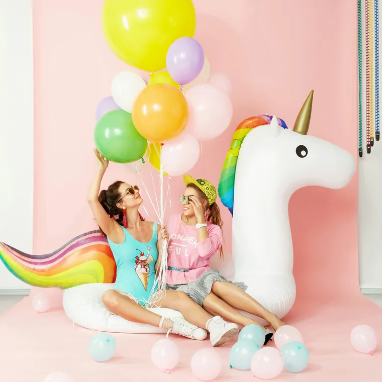 Large unicorn pool float surrounded by pastel balloons.