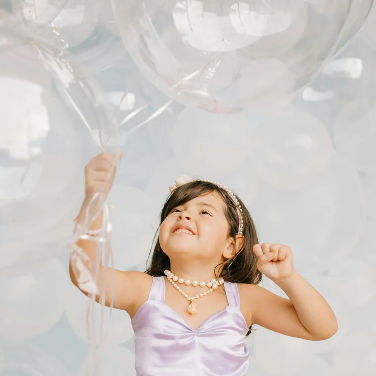 Child reaching up towards oversized clear bubble balloons.