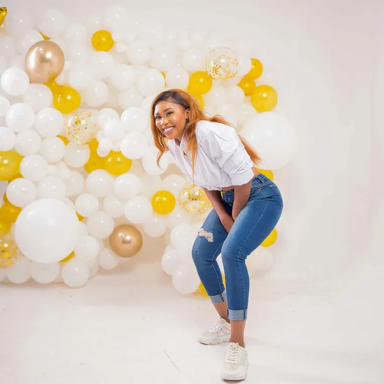 Woman posing in front of a white and gold balloon wall.